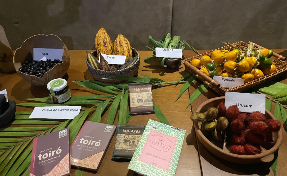 Food produced by Brazilian families and community cooperatives laid out on a table, including fruits and chocolate