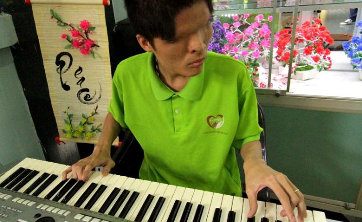 A keyboard player, blind from birth due to a genetic defect induced by Agent Orange, performing at the War Remnants Museum. Photo: Mick Grant.